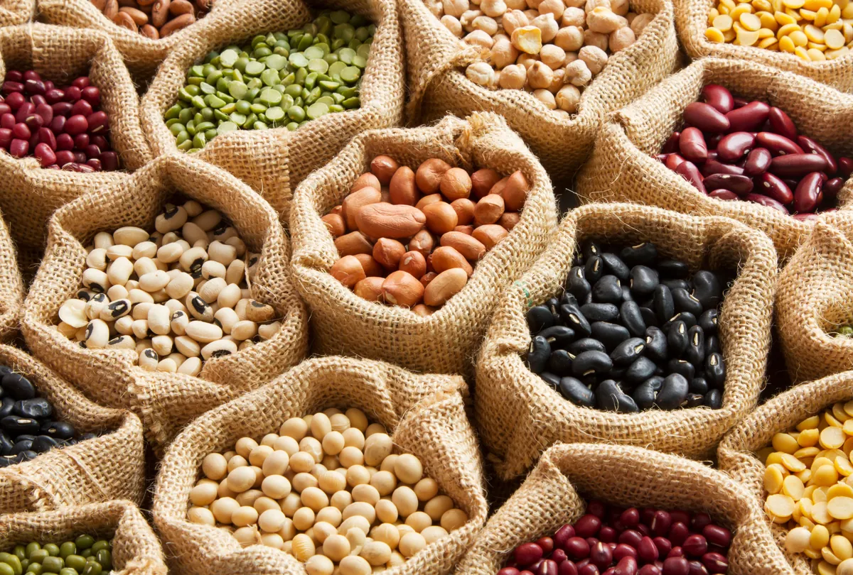 Overhead view of colorful legumes and beans in burlap sacks at market.