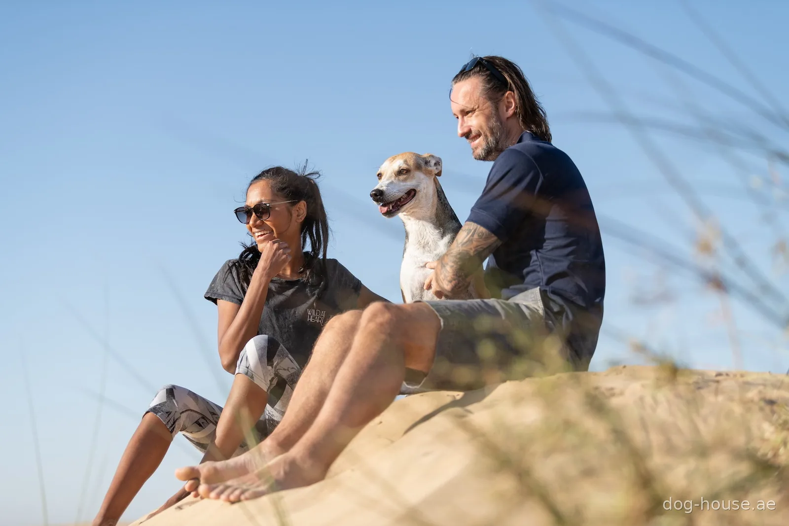 Ota and Hanah Sebesta sitting on a dune with Misha, their dog