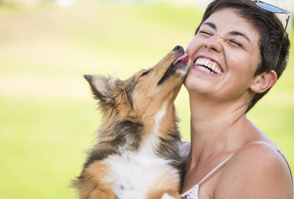 woman laughing as dog licks face outdoors 2026 03 19 09 25 06 utc